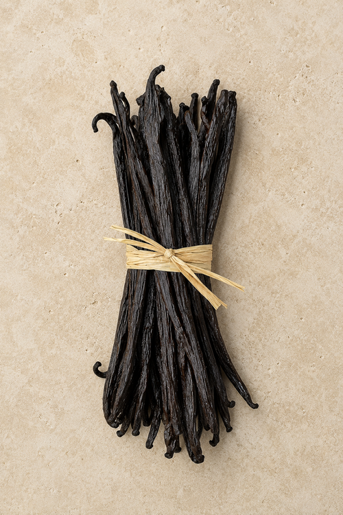 20 luna vanilla beans tied with raffia on a beige background