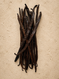 Stack of luna vanilla extract grade vanilla beans on a beige surface