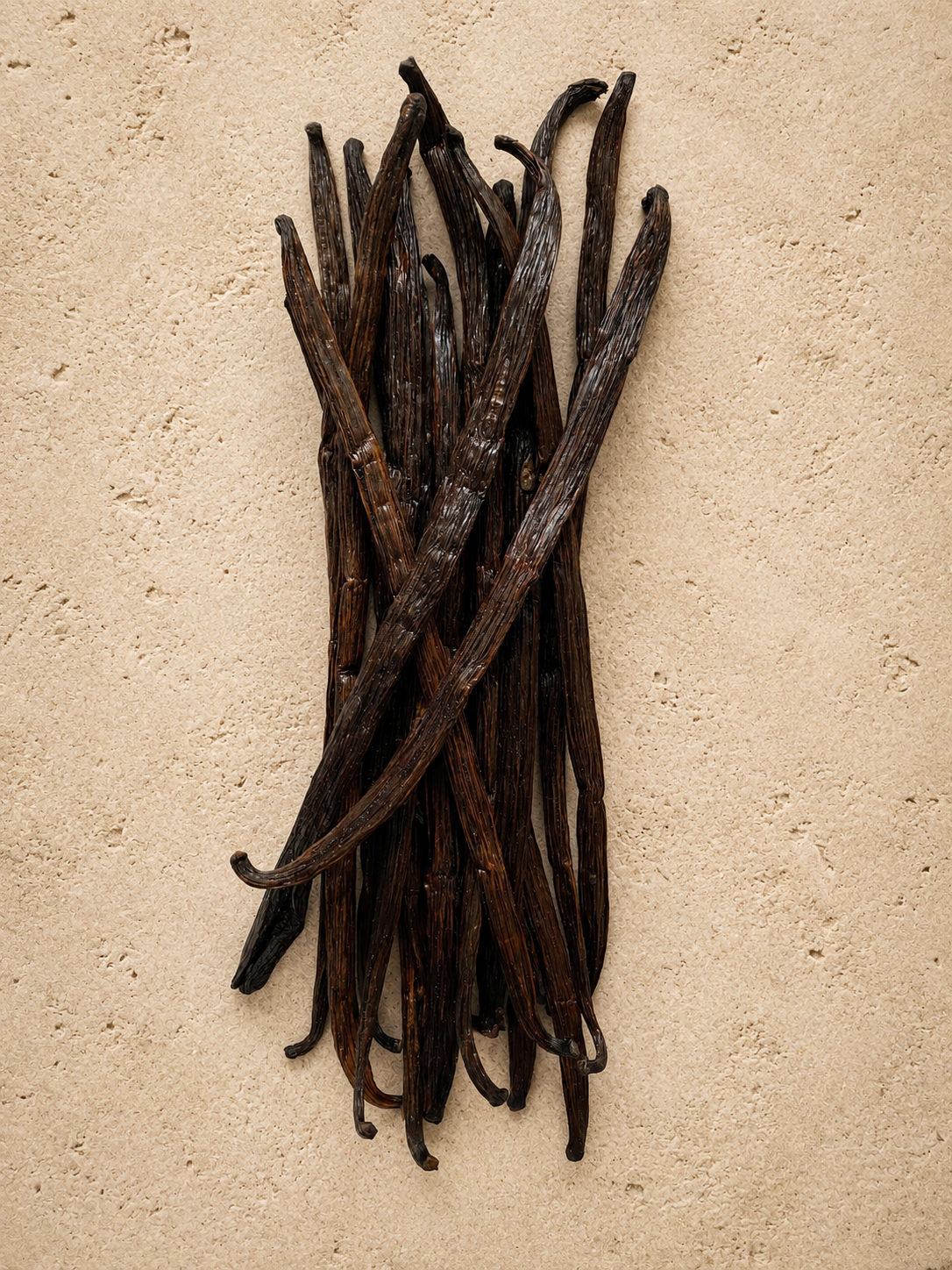 Stack of luna vanilla extract grade vanilla beans on a beige surface