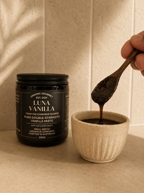 Luna Vanilla paste being scooped into a small bowl with a jar of Luna Vanilla in the background.